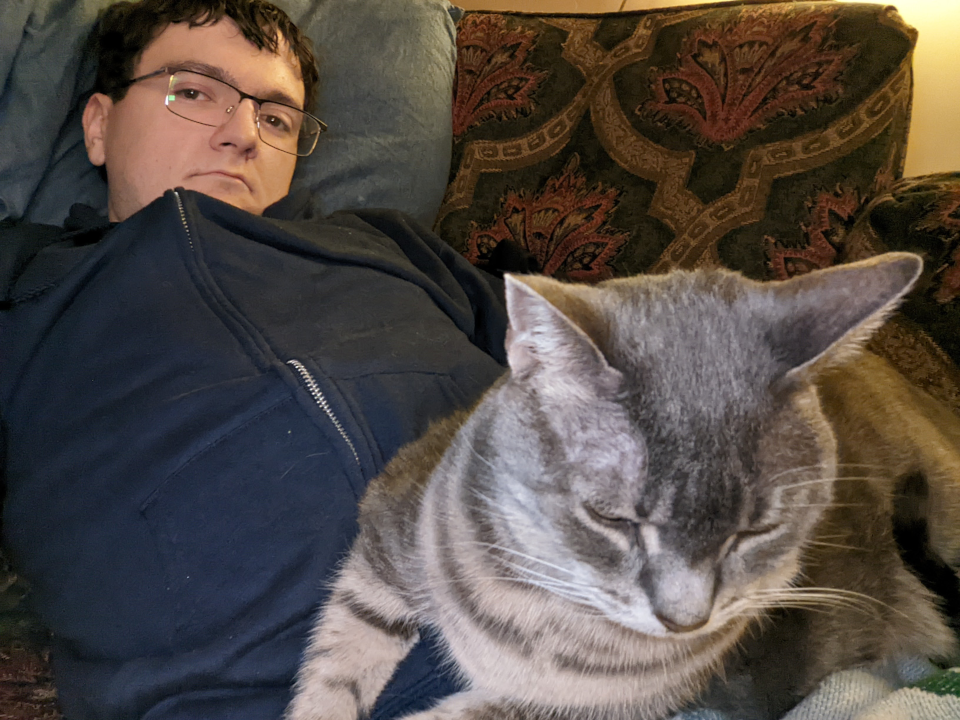 Henry chilling out with a gray tabby cat in his lap